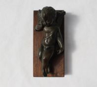 A bronze model of a recumbent cupid, with his head resting on a pillow,