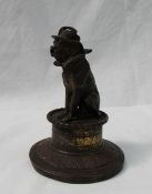 A bronze model of a clown dog wearing a hat and ruff seated on a drum,