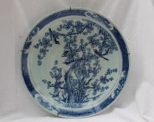 A large Japanese blue and white porcelain charger, decorated to the centre with birds amongst trees,