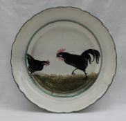 A Llanelly pottery plate painted with a hen and cock in black, within a green line border,