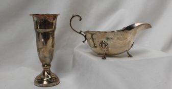 A George V silver sauce boat, with a shaped edge and scrolling handle on leaf capped hoof feet,