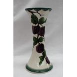 A Llanelly pottery waisted vase with a flared top and spreading base painted with plums on a branch,