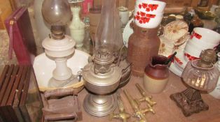 An opaque glass oil lamp together with a collection of oil lamps, flat irons, brass barrel taps,