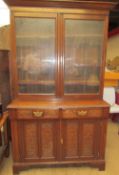 An Edwardian oak bookcase with a moulded cornice above a pair of glazed doors,