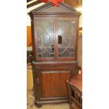 An 18th century oak standing corner cupboard with a moulded cornice above a pair of astragal glazed