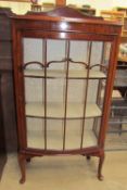 A 20th century mahogany display cabinet with a domed form with a glazed door and glazing bars on