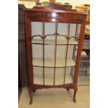 A 20th century mahogany display cabinet with a domed form with a glazed door and glazing bars on