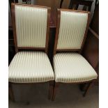 A pair of modern dining chairs with striped cream upholstery