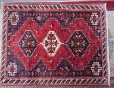 An Iranian red ground rug with three interlocking medallions with guard stripes together with