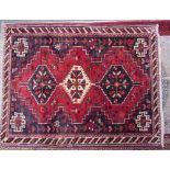 An Iranian red ground rug with three interlocking medallions with guard stripes together with