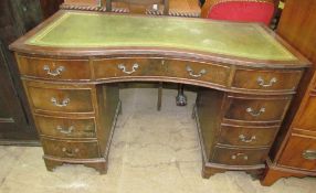 A reproduction mahogany desk with a green leather inset top and two banks of drawers on bracket