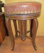 An Edwardian mahogany piano stool with a circular pad upholstered top