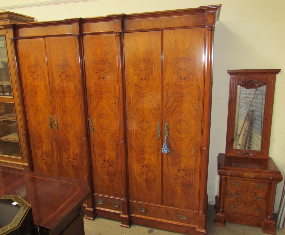 A large modern walnut wardrobe with a moulded cornice above five doors with drawers to the base on