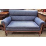 An Edwardian upholstered two seater settee with scroll over arms with a walnut carved frame and