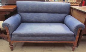 An Edwardian upholstered two seater settee with scroll over arms with a walnut carved frame and