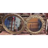A gilt framed wall mirror of oval form decorated with flowers and leaves,