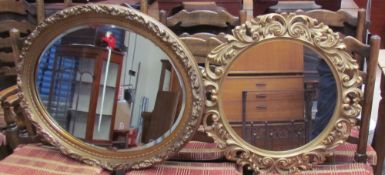 A gilt framed wall mirror of oval form decorated with flowers and leaves,