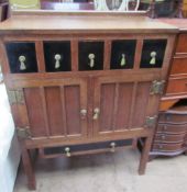 An oak Arts and Crafts style side cabinet with five drawers and two cupboards on square legs