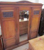 An Edwardian oak triple wardrobe with a central mirrored door and two doors either side