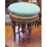An Edwardian walnut piano stool with a circular pad upholstered top on four turned splayed legs