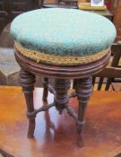 An Edwardian walnut piano stool with a circular pad upholstered top on four turned splayed legs