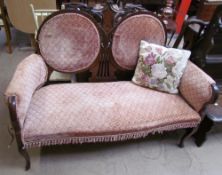 An Edwardian two seater settee with upholstered panelled back and seat with scroll over arms