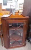 A reproduction mahogany hanging corner cupboard with an astragal glazed door,