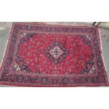 A red ground rug with interlaced flowers and a floral border with guard stripes