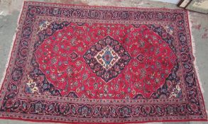 A red ground rug with interlaced flowers and a floral border with guard stripes