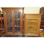 An oak hanging corner cupboard with a pair of glazed doors with glazing bars,