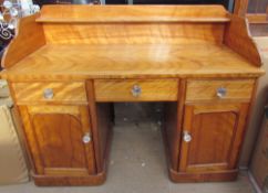 A satin walnut desk, with a raised back and shelf above a central drawer,