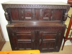 An 18th century oak court cupboard, the planked top above a carved frieze and turned columns,