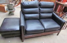 A black leather upholstered two seater settee together with a footstool