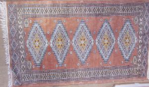 A rug with an orange ground and geometric medallions together with a small red ground prayer rug