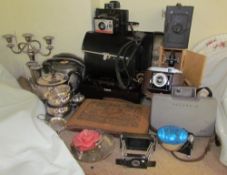 An electroplated three piece tea set together with a candelabra, Polaroid cameras, other cameras,