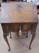 A 20th century walnut bureau with a sloping fall and fitted interior on cabriole legs and pad feet