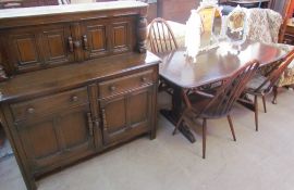 An Ercol dark oak dining suite comprising a dining table,