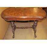A Victorian walnut card table with a hinged shaped top with a baize interior on carved and turned