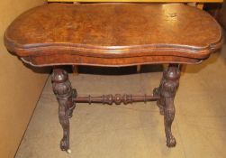 A Victorian walnut card table with a hinged shaped top with a baize interior on carved and turned