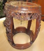 An early 20th century Chinese carved rosewood seat of barrel shape ornately carved and pierced with