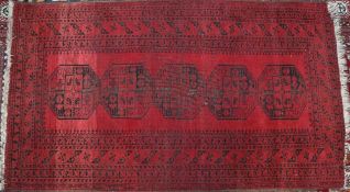 A red ground Turkoman rug with five geometric medallions to a red ground