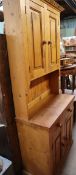 A modern pine kitchen dresser with cupboards to the top,