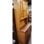 A modern pine kitchen dresser with cupboards to the top,
