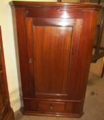 A 19th century mahogany hanging corner cupboard with a panelled door,