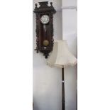 A Vienna regulator type wall clock together with a standard lamp,