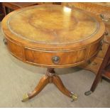 A 20th century yew wood reproduction drum table with circular leather inset top on a tripod,