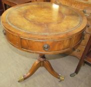 A 20th century yew wood reproduction drum table with circular leather inset top on a tripod,