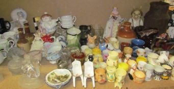 A collection of pottery egg cups together with novelty tea pots, commemorative mugs, jugs,
