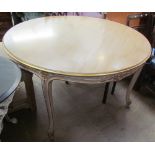 A 20th century dining table of round form with a gilt edge on leaf carved legs