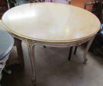 A 20th century dining table of round form with a gilt edge on leaf carved legs